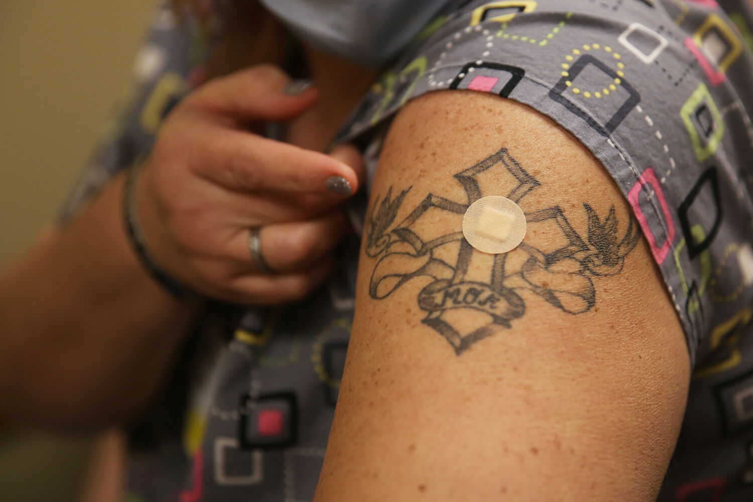 Fran Bowe looks down at her bandaid after receiving her shot